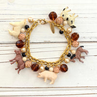 Gold chain charm bracelet with farm animal charms, pearls, peach rhinestone beads and brown faceted beads.