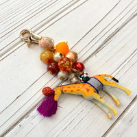 Cute beaded bag charm with embellished giraffe figurine and a mix of beads in orange and red tones.