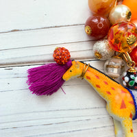 Cute beaded bag charm with embellished giraffe figurine and a mix of beads in orange and red tones.