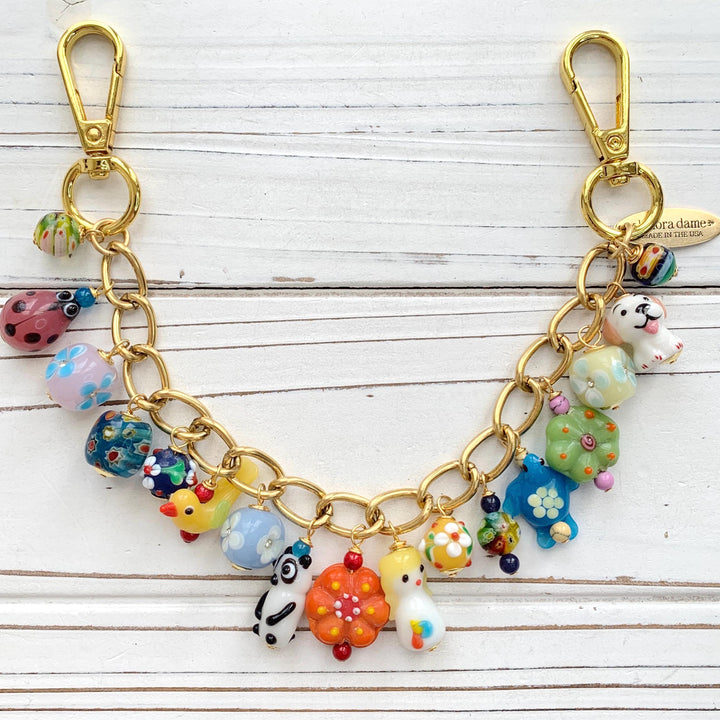 Tiny lampwork glass animals and lampwork floral beads hanging on a gold bag chain with trigger clasps on either end. Cute colorful bag chain for handbags.