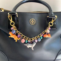 Cat bag charm with cat charms and a mix of purple and green beads on a gold chain. Cute bag chains for handbags. Purple bag cham.
