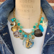 Mermaid charm necklace for vacation outfit ideas. Aqua blue beads, seashells, starfish, anchor charm and mermaid pendant necklace for summer.