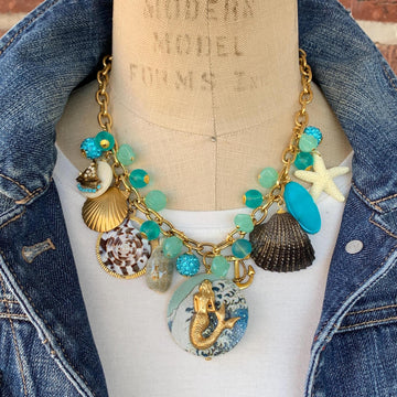 Mermaid charm necklace for vacation outfit ideas. Aqua blue beads, seashells, starfish, anchor charm and mermaid pendant necklace for summer.