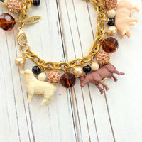 Miniature farm animal charms on a gold chain charm bracelet.
