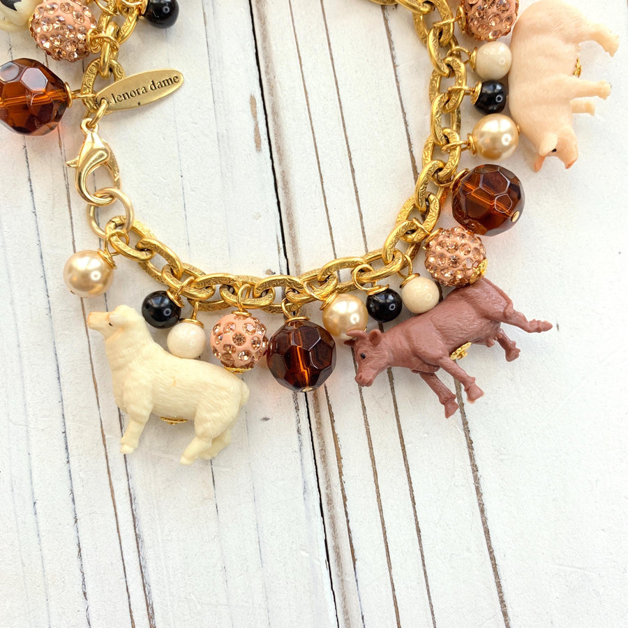 Miniature farm animal charms on a gold chain charm bracelet.
