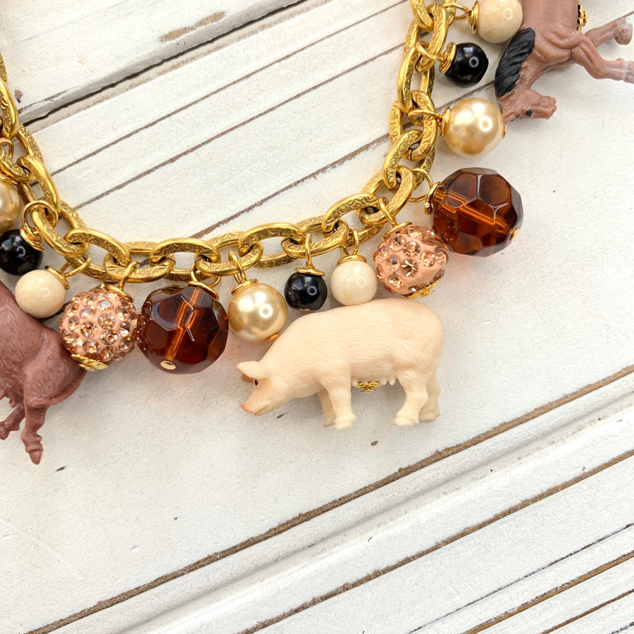 Miniature pig charm on a gold chain charm bracelet.