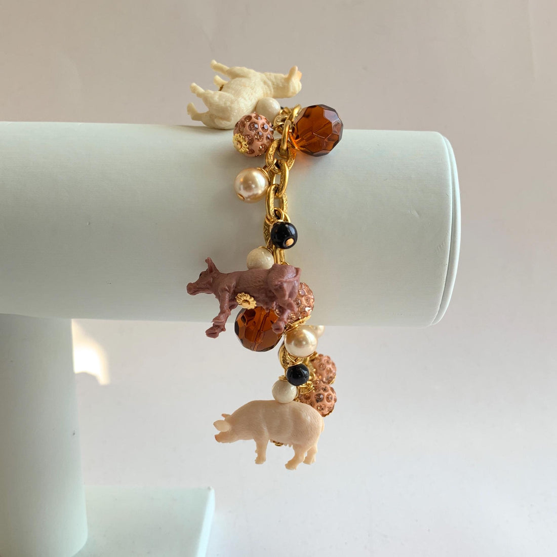 Gold chain charm bracelet with farm animal charms, pearls, peach rhinestone beads and brown faceted beads.