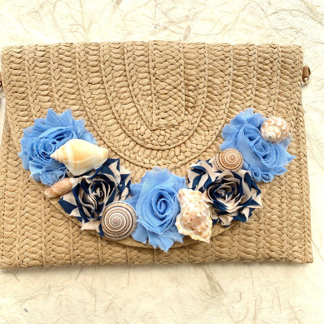 Straw woven clutch purse for women with removable strap. Embellished straw crossbody bag with seashells and fabric flower details.