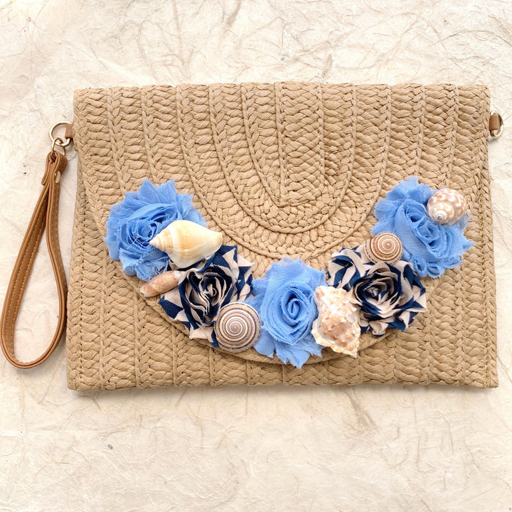Straw woven clutch purse for women with removable strap. Embellished straw crossbody bag with seashells and fabric flower details. Cute straw clutch purses for women 2025.