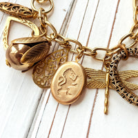 Chunky gold charm bracelet filled with a mix of gold charms in different shapes and sizes hung on a gold cable chain with lobster clasp. Lenora Dame jewelry made in the USA.
