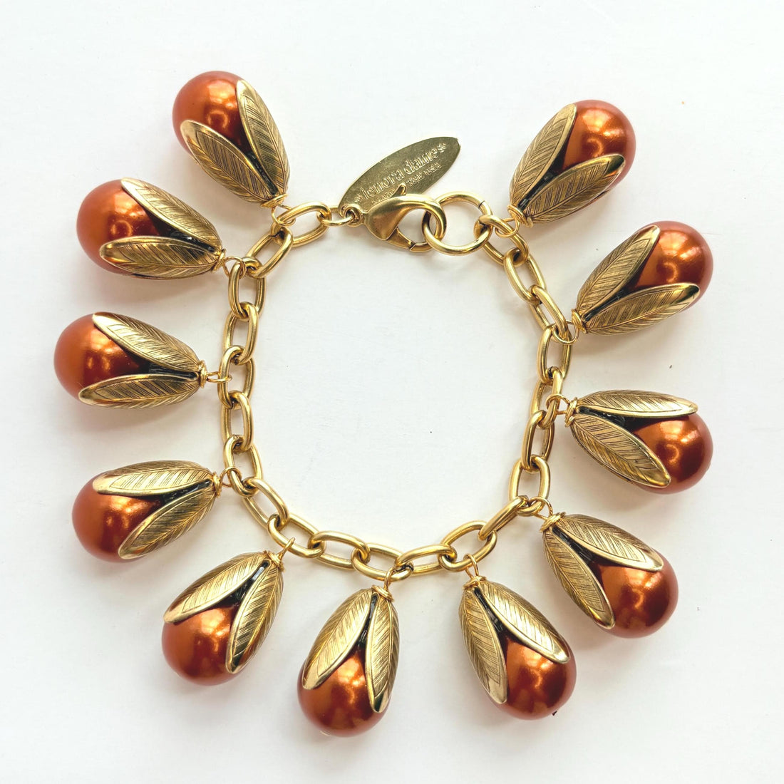 Gold chain bracelet with shiny pumpkin orange pearls encased in gold leaf bead caps. Lenora Dame bracelets handmade in the USA.
