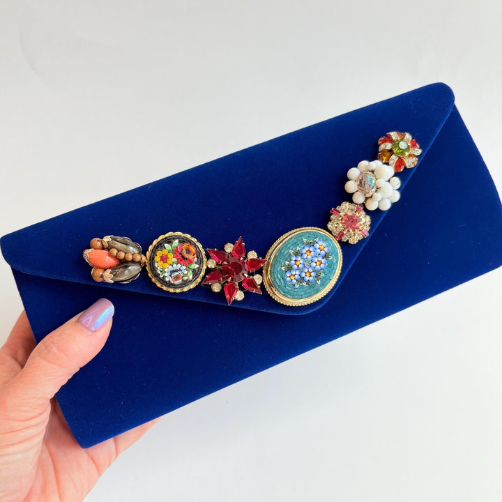 Royal blue velvet clutch purse detailed with seven vintage pearl and rhinestone earrings and miniature mosaic brooches.